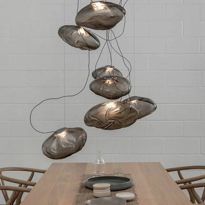 Modern decorative chandelier with glass shade and fabric design, available in amber, clear, or smoke grey.
