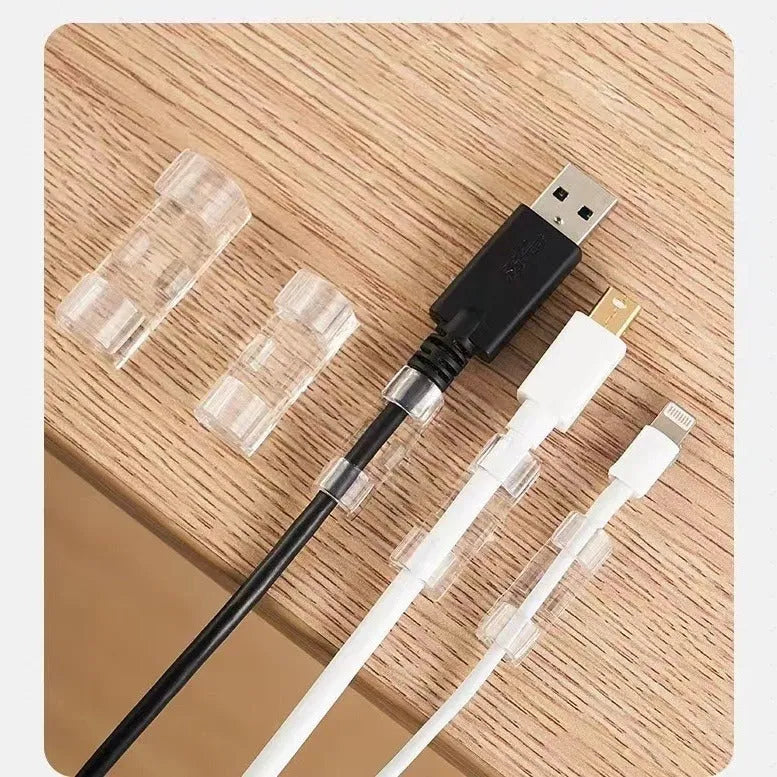 Transparent plastic self-adhesive wire holder routing snap clip on a desk surface with a white cable inserted