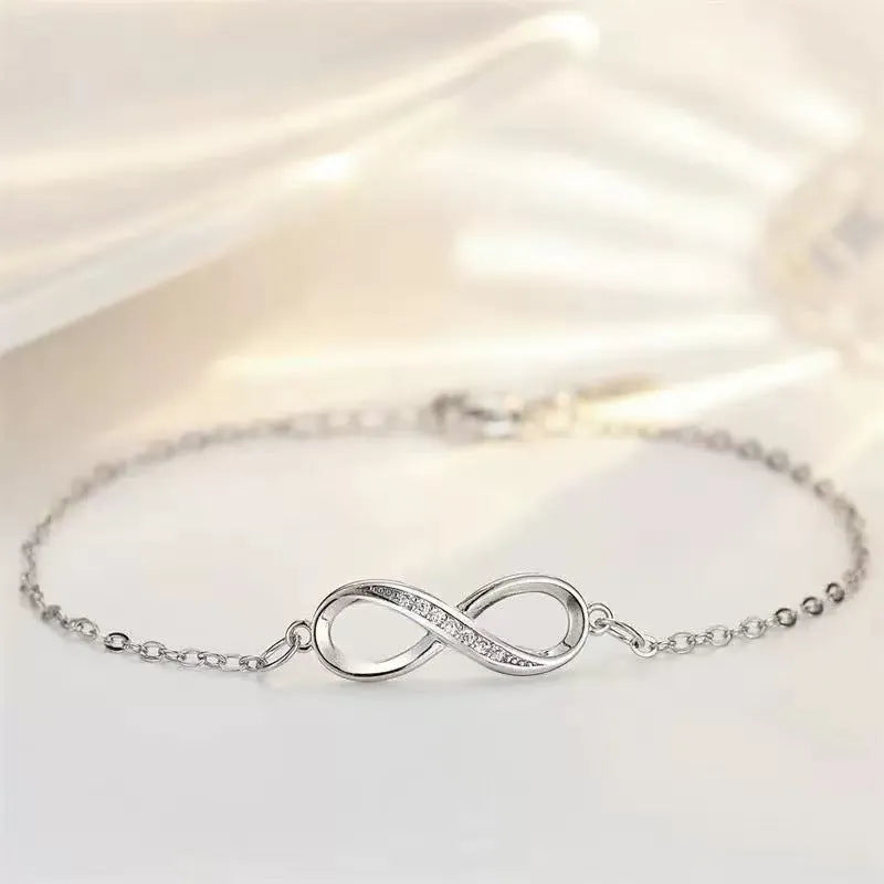 Silver copper Mobius strip diamond ring push-pull bracelet with lucky cat charm on display.