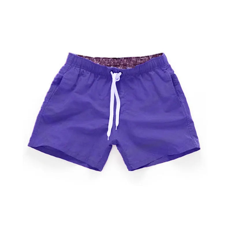 Men's polyester straight-leg surf shorts on a hanger, available in multiple solid colours.