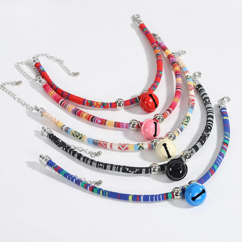 Colourful adjustable pet collar with ethnic patterns and a small metal bell attached, shown in multiple colour options.
