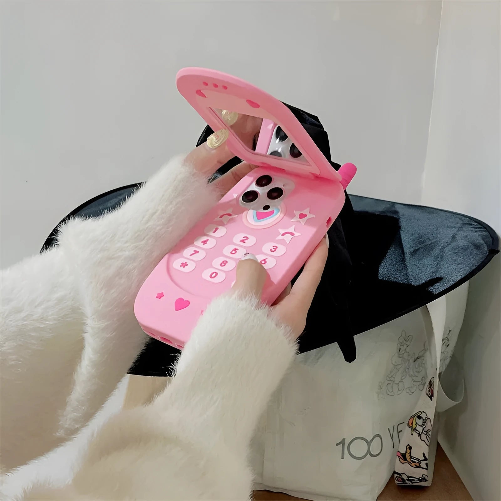 Light pink silicone flip phone shaped mirror case for iPhone on a white background.