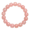 Pink natural crystal bracelet with polished geometric barrel-shaped beads on a wrist.