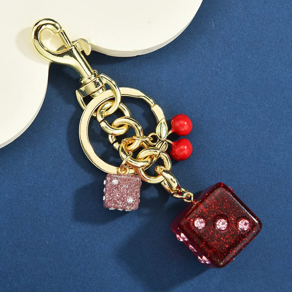 Square metal keychain pendant with a vintage red and white cherry dice pattern.