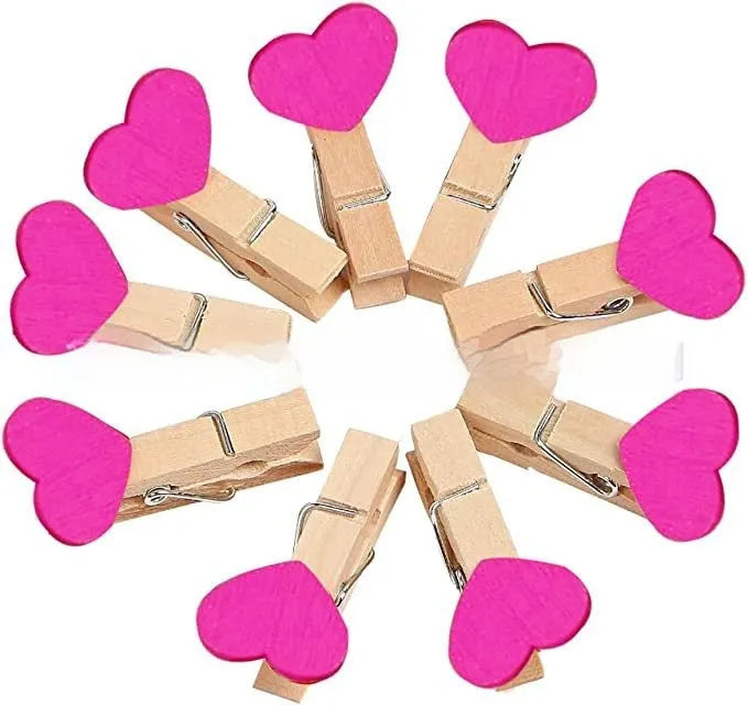 Five handmade solid wood heart-shaped clips in red, pink, white, yellow colours on a wood surface.
