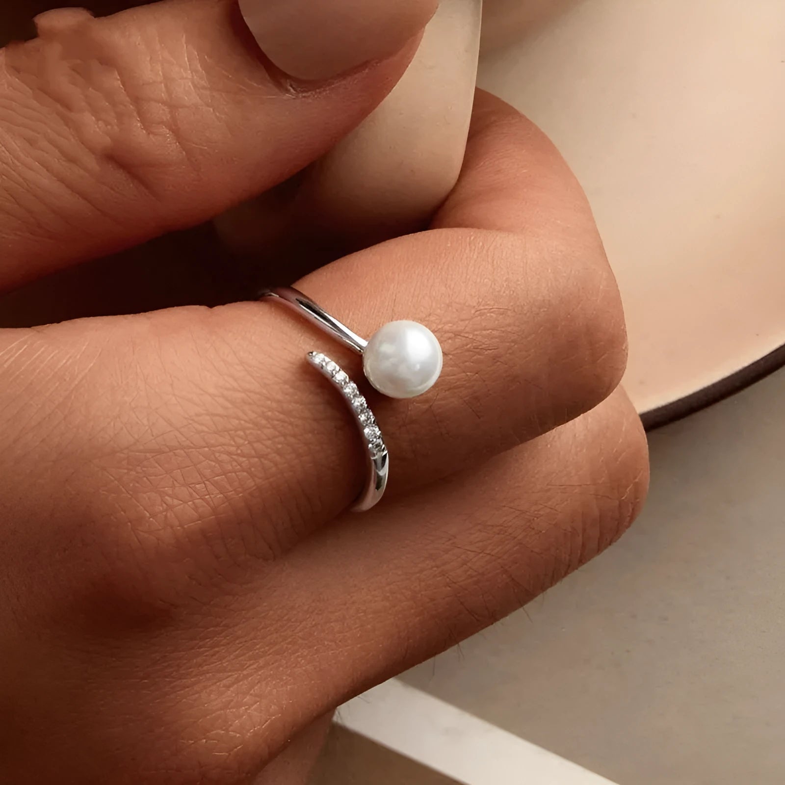 Sterling silver adjustable ring with a natural pearl on an open loop band.