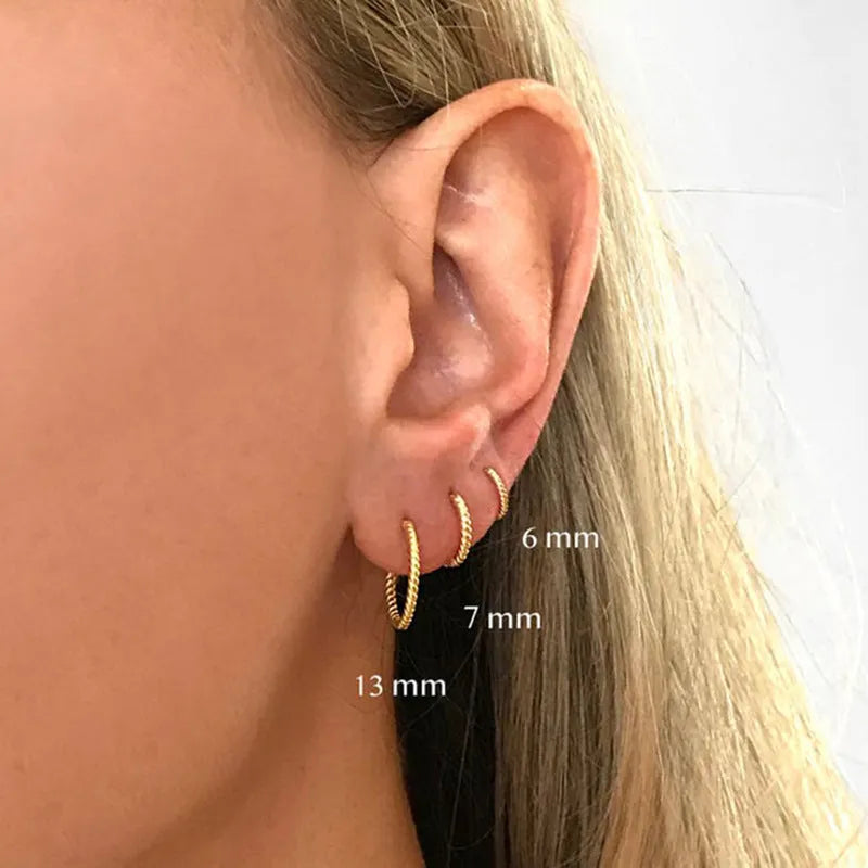 Close-up of twisted sterling silver hoop earrings showing the textured string design.