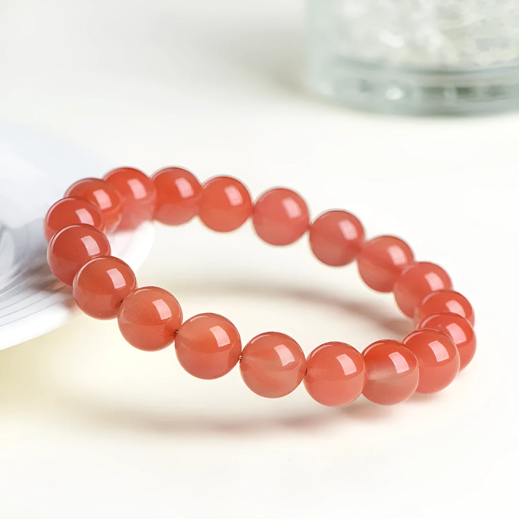 Natural South Cherry Red Agate beaded bracelet on a wrist, showing polished scattered beads on an elastic cord.