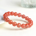 Natural South Cherry Red Agate beaded bracelet on a wrist, showing polished scattered beads on an elastic cord.