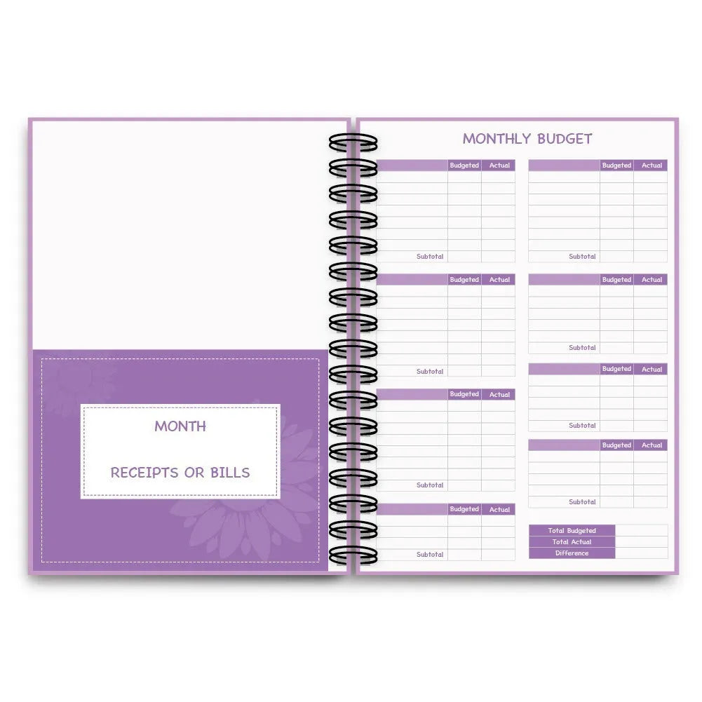 Purple coil-bound financial planning notebook open on a desk with pen, stickers, and paper clips.