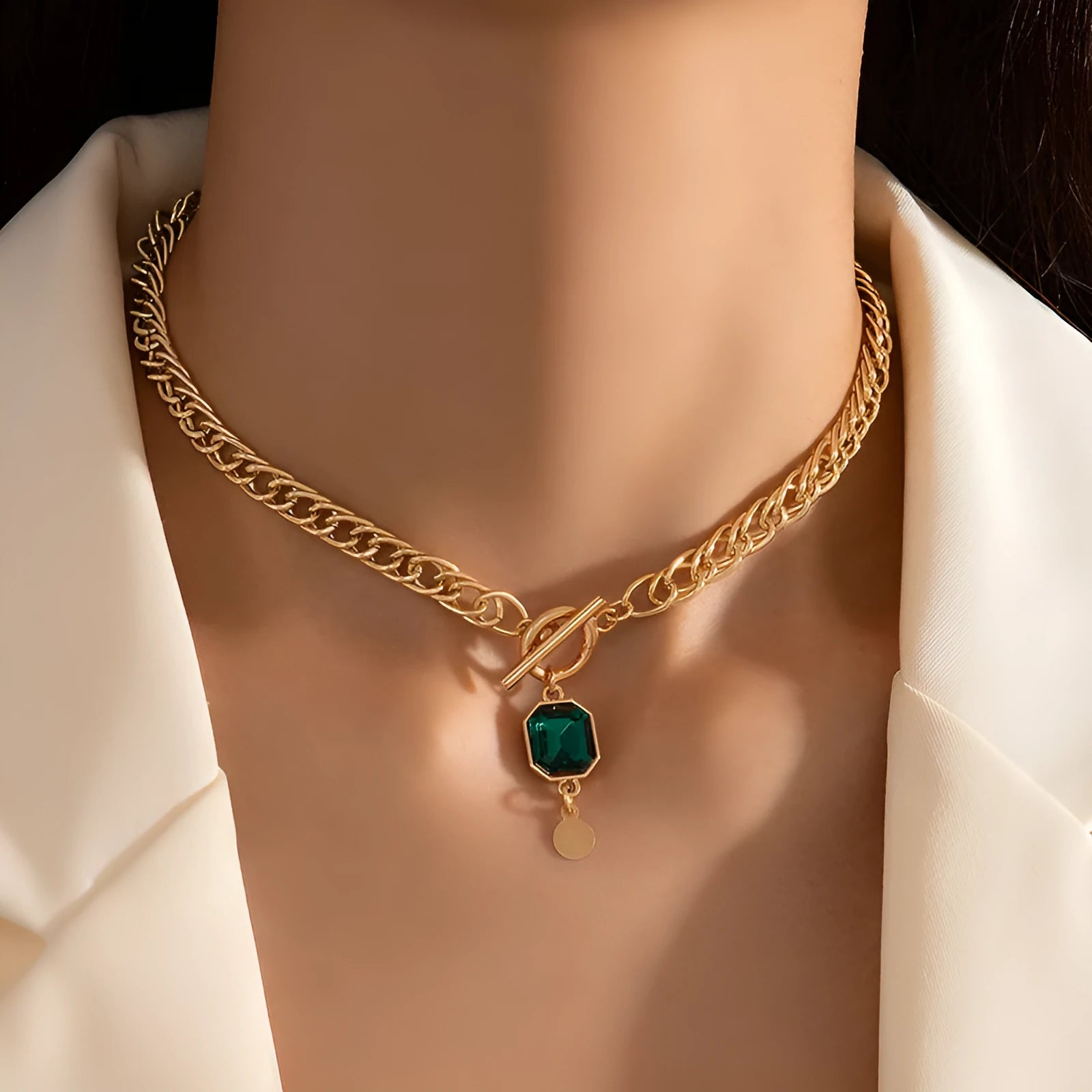Gold titanium steel necklace with round emerald green zircon pendant on a Cuban link chain.