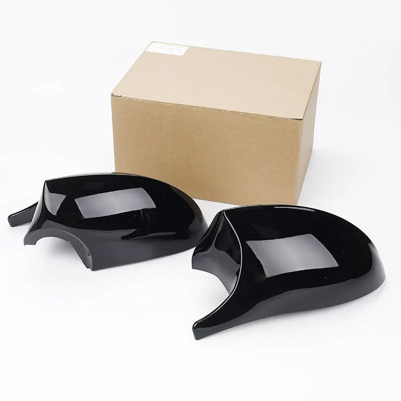 A pair of black and carbon pattern ABS plastic rearview mirror housing shells for a BMW 3 Series E90.