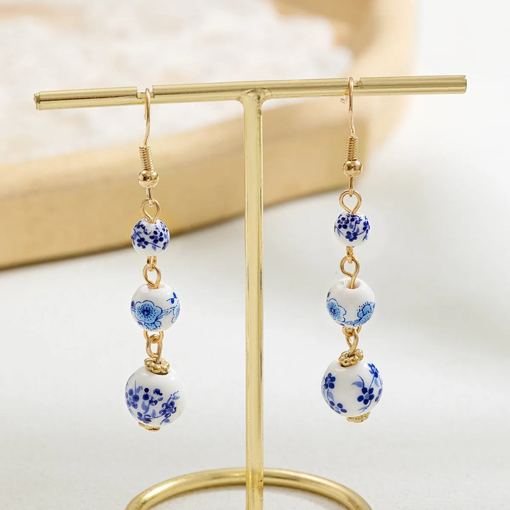 Blue and white porcelain ceramic beads long drop earrings on display with geometric round shape and alloy backing