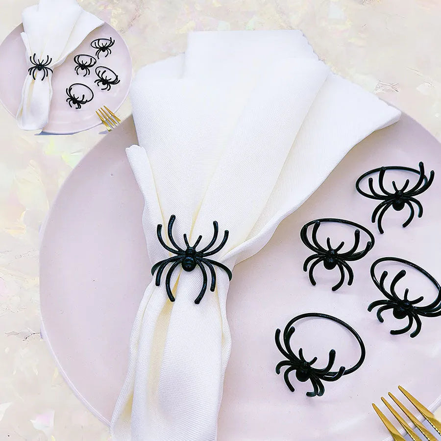 Set of six black metal spider-shaped napkin rings for Halloween table decoration.